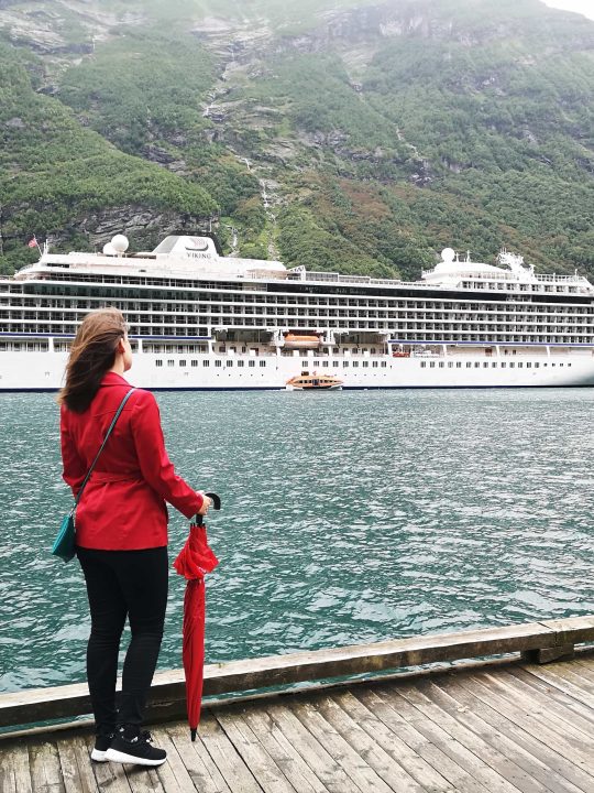 Viking Sea docked in Geiranger Emma Cruises Girl in red coat looking at cruise ship