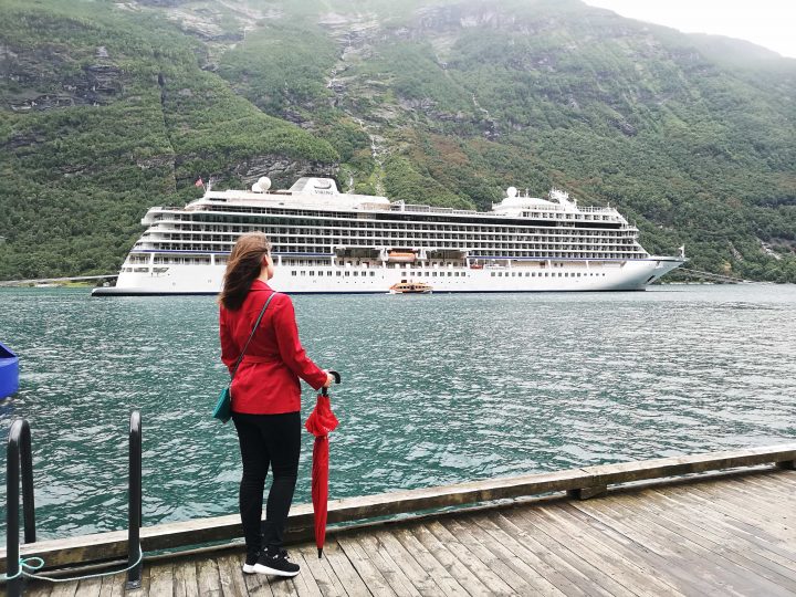 Viking Sea docked in Geiranger Emma Cruises Girl in red coat looking at cruise ship