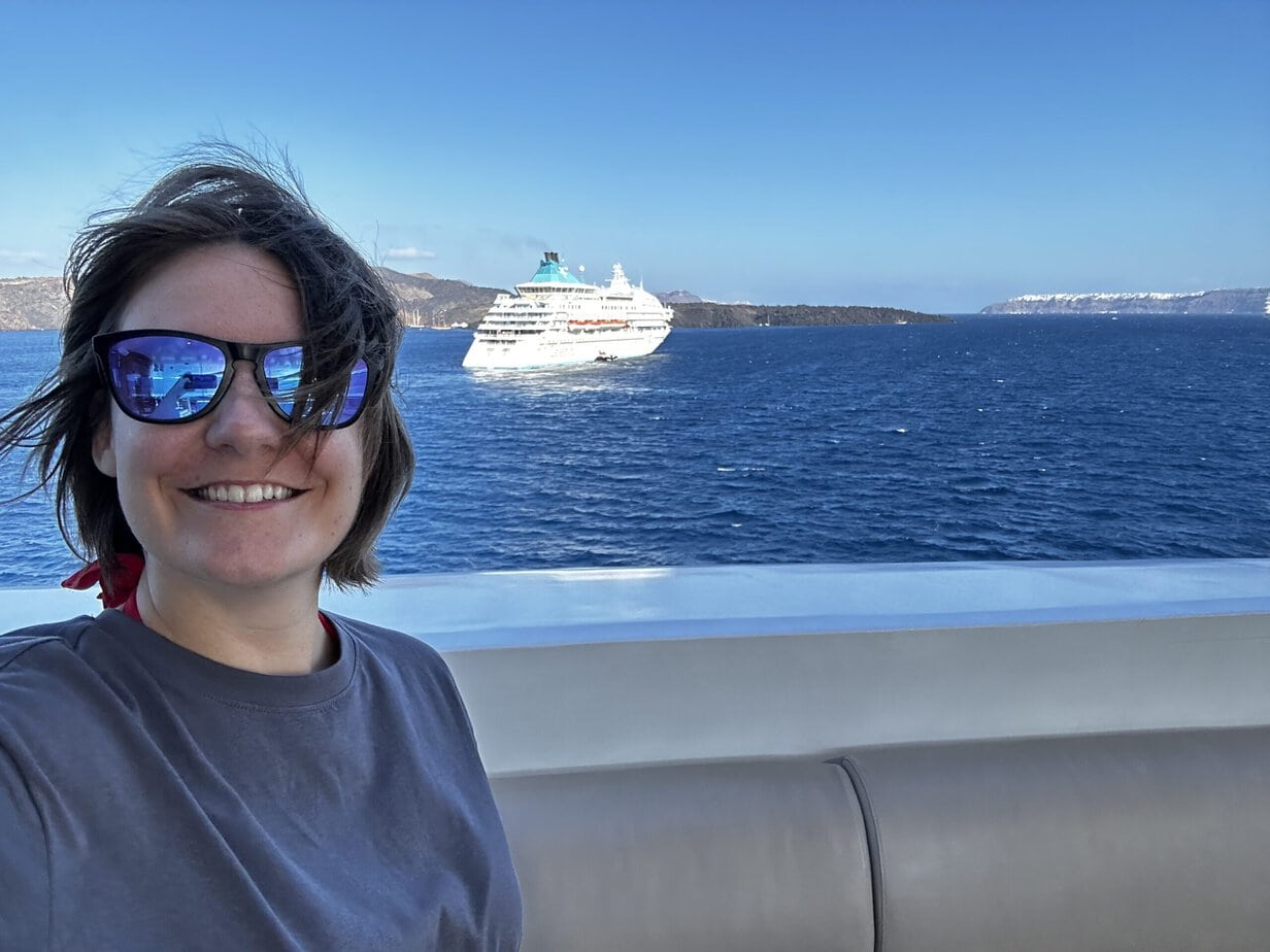 Emma cruises in Sunglasses with a ship
